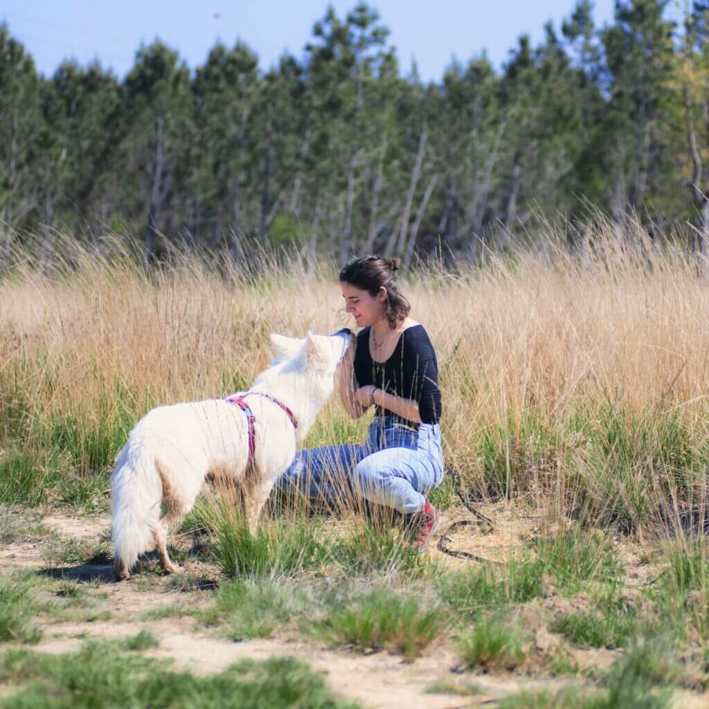 Zoé est accroupie à côté d'un chien blanc